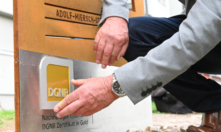 Pressefoto DGNB-Zertifikat Hand befestigt DGNB-Plakette an Tafel